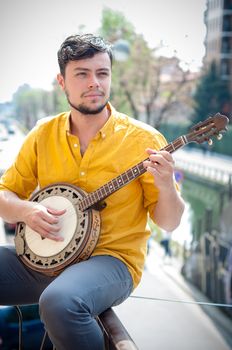 hipster young man playing banjo in the city