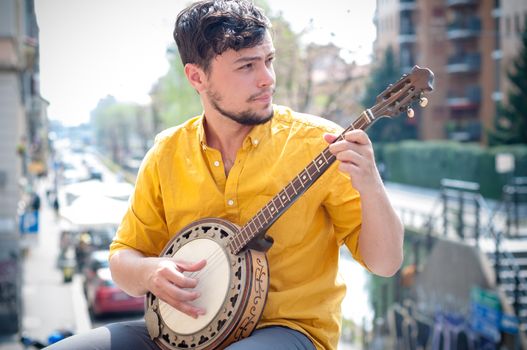 hipster young man playing banjo in the city