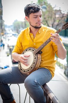 hipster young man playing banjo in the city