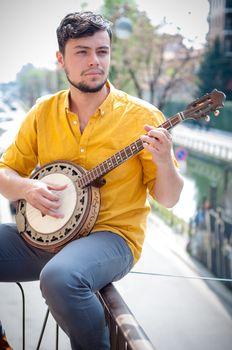 hipster young man playing banjo in the city