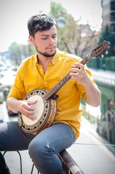 hipster young man playing banjo in the city