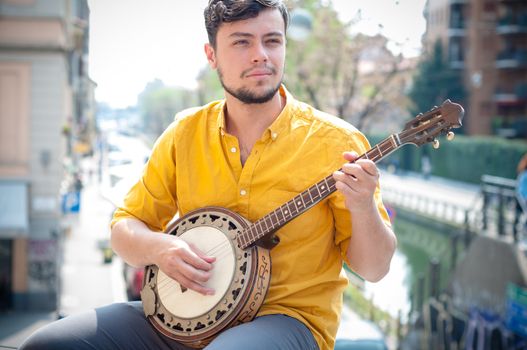 hipster young man playing banjo in the city