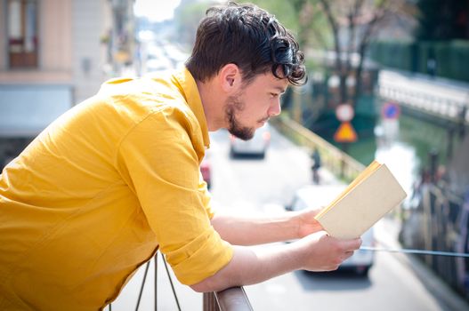young man reading book on the balcony