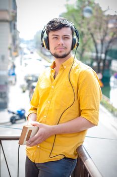 young man reading book and listening music on the balcony