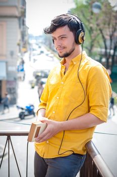 young man reading book and listening music on the balcony