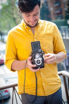 hipster young man with old camera on the balcony