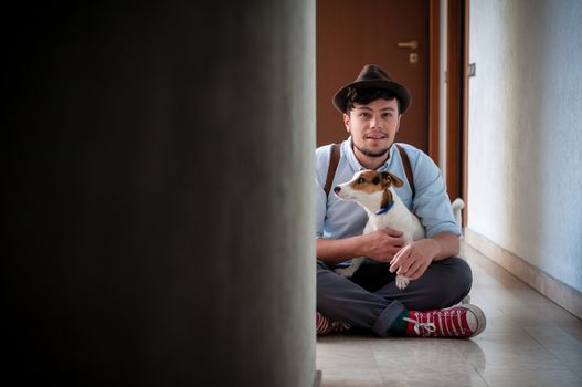 hipster young man posing with jack russell dog in a hallway