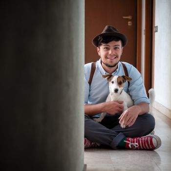 hipster young man posing with jack russell dog in a hallway