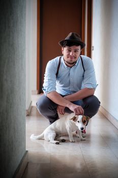 hipster young man posing with jack russell dog in a hallway