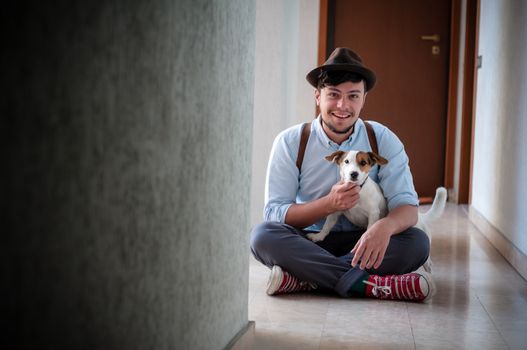 hipster young man posing with jack russell dog in a hallway