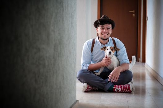 hipster young man posing with jack russell dog in a hallway