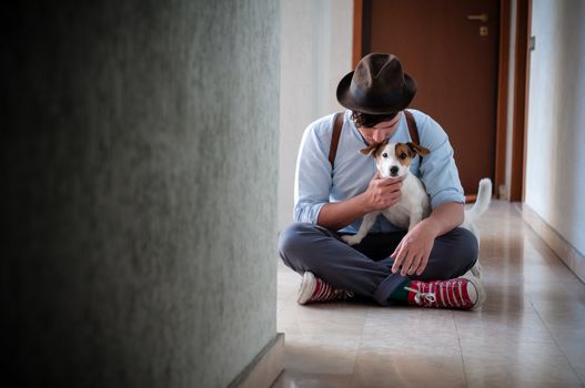 hipster young man posing with jack russell dog in a hallway