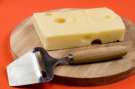 Cheese with a knife on a wooden board