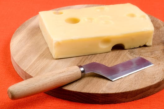 Cheese with a knife on a wooden board