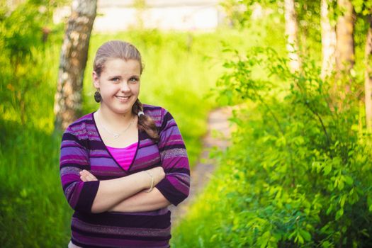 Girl Standing On A Forest Path Road. Her Hands Crossed