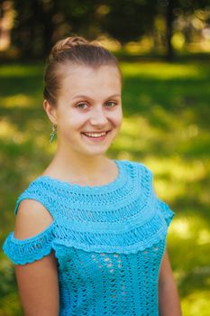 Closeup portrait of beautiful young girl in blue knitted dress in the park outdoor