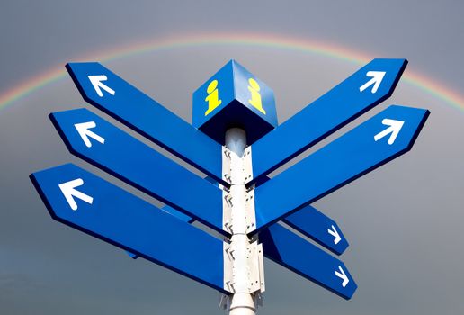 Blank directional road signs over rainbow