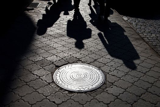 Shadows of people walking street in morning light