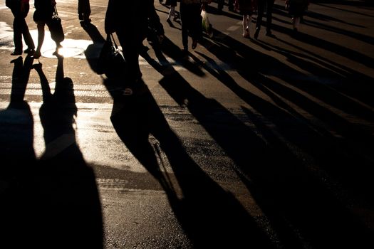 Shadows of people walking street in morning light