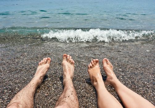 Pair legs relaxing on pebbles sea beach
