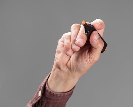 A hand holding a orange marker on gray background