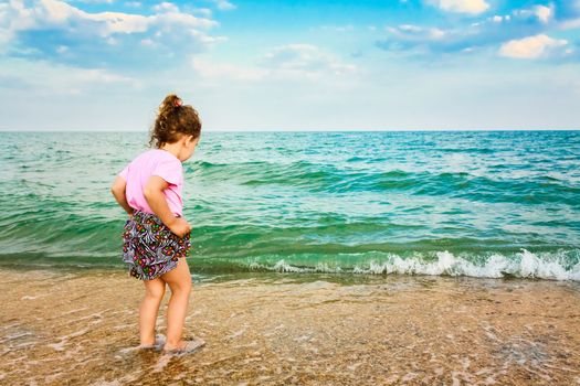 Happy active child girl having fun on beautiful beach. Child running on water at ocean beach.