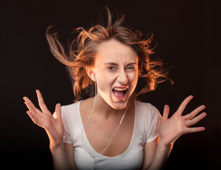 Beautiful Woman Listening Music and screams on a dark background