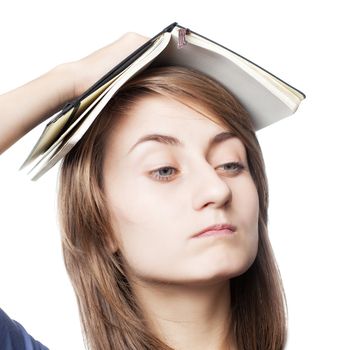 Education. Tired girl holds a notebook on her head on a white background