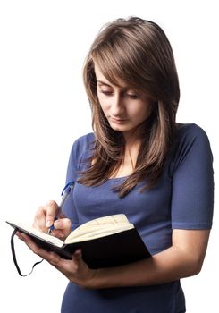 Young woman writing in notebook on a white background