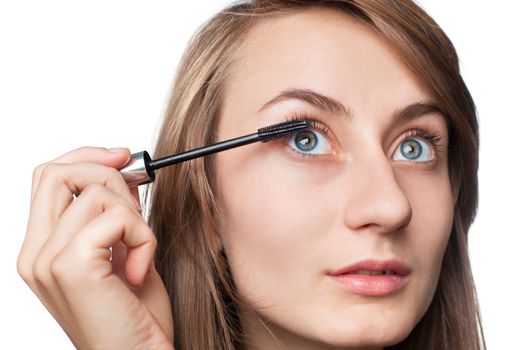 Woman applying mascara on her eyelashes