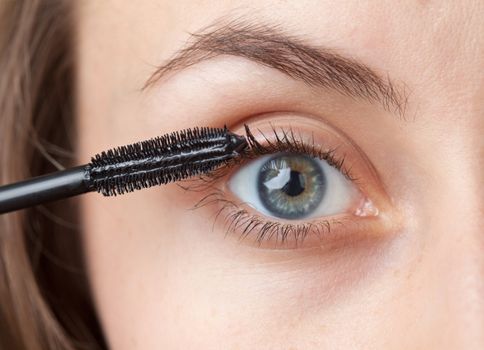 Woman applying mascara on her eyelashes