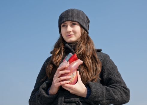 Young woman with a heart in her hand against the blue sky. Focus mainly on the face.