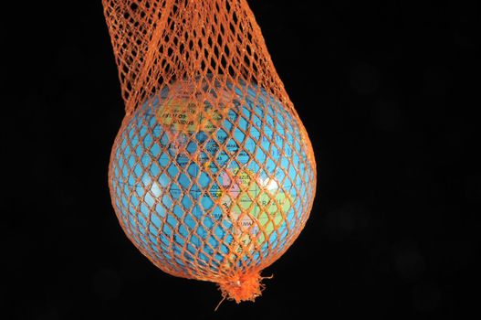 Globe in a green net on a dark black bacground