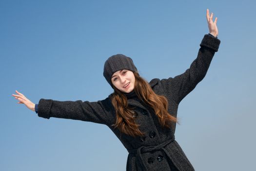  Pretty young woman with arms raised against blue sky