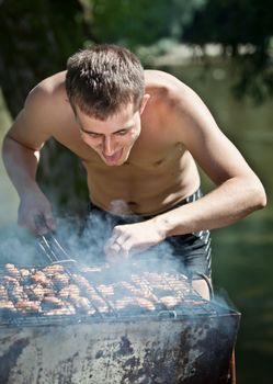 Young man preparing barbecue outdoors