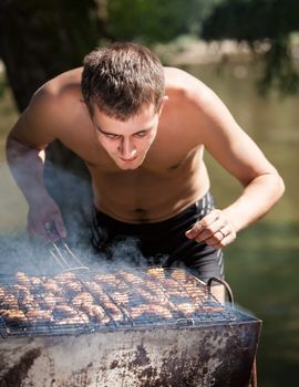 Young man preparing barbecue outdoors