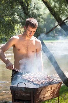 Young man preparing barbecue outdoors