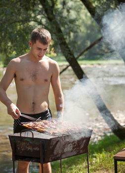 Young man preparing barbecue outdoors