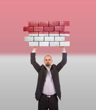 Businessman holding a large piece of a brick wall, flag of Indonesia, isolated on national flag