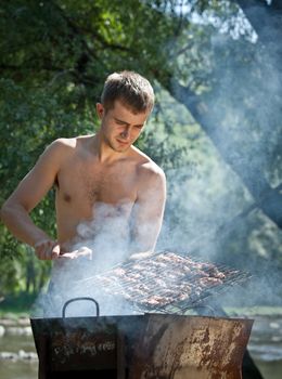 Young man preparing barbecue outdoors