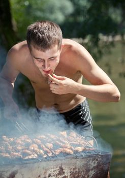 Young man preparing barbecue outdoors