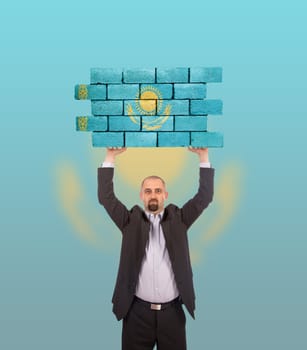 Businessman holding a large piece of a brick wall, flag of Kazakhstan, isolated on national flag