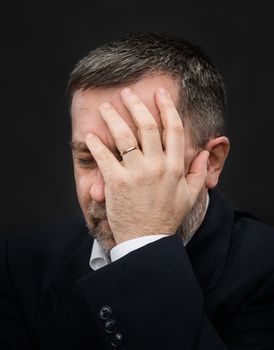 Headache. Portrait of an elderly man with face closed by hand