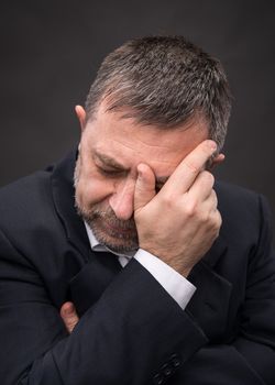 Headache. Portrait of an elderly man with face closed by hand