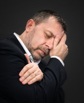 Headache. Portrait of an elderly man with face closed by hand