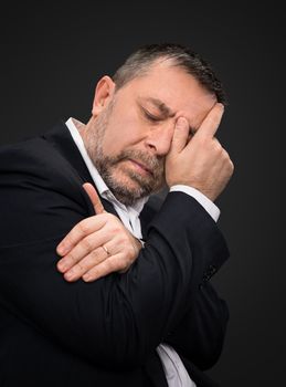 Headache. Portrait of an elderly man with face closed by hand