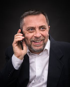 Smiling middle-aged businessman speaks on a mobile phone and gesturing