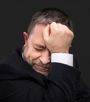 Headache. Portrait of an elderly man with face closed by hand