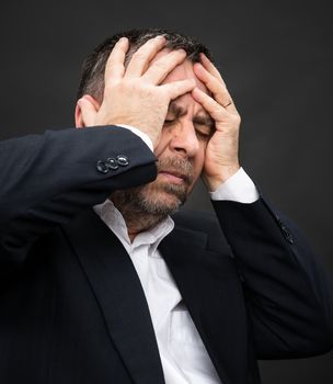 Headache. Portrait of an elderly man with face closed by hands