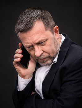 Handsome middle-aged business man speaks on a mobile phone and gesturing